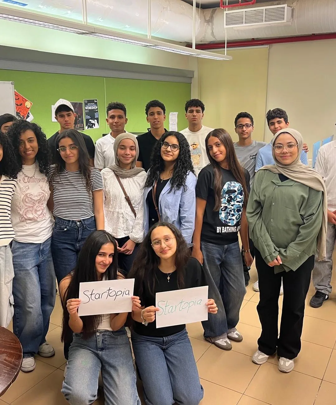 The Startopia Bootcamp cohort at the American University in Cairo, two students holding handwritten Startopia signs