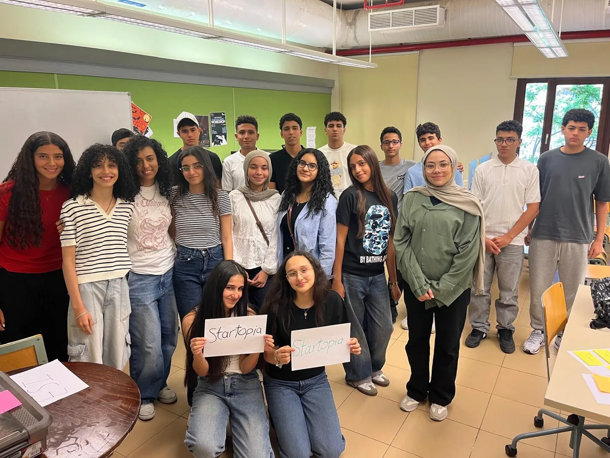 The full cohort of 21 young founders at the Startopia Bootcamp, American University in Cairo, holding Startopia signs