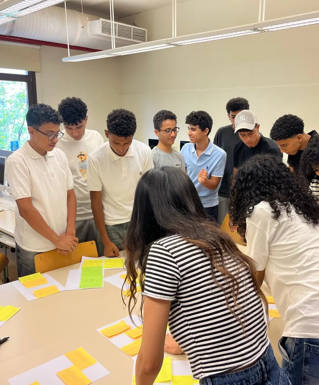 A Buildathon cohort gathered around one table, mapping problems with sticky notes