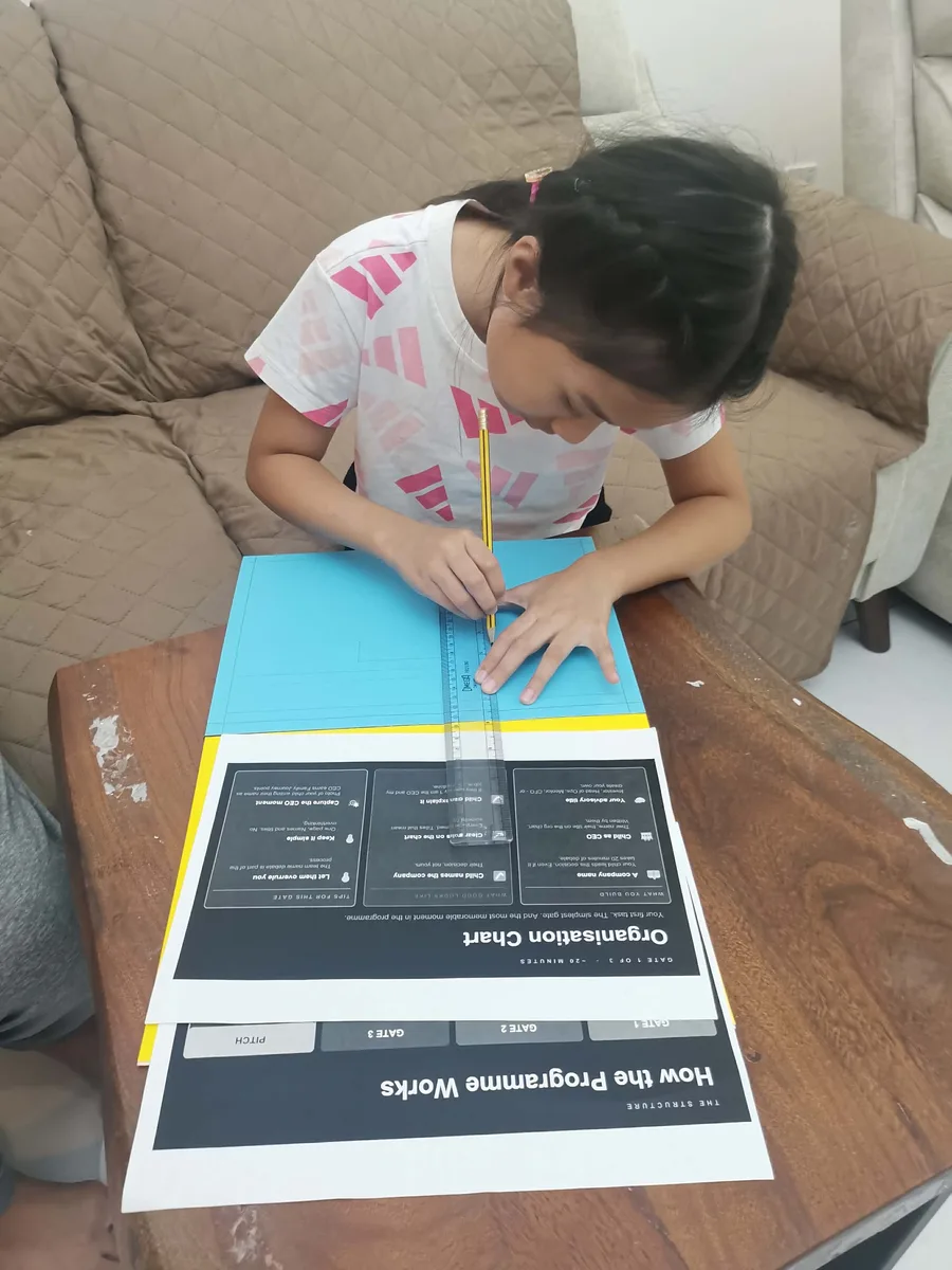 A child working through Gate 1 of the GEMS Family Innovation Challenge at home, filling in the organisation chart