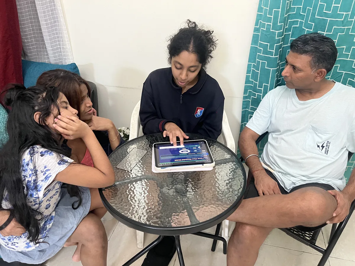 A family reviewing their pitch deck together as part of the GEMS Family Innovation Challenge