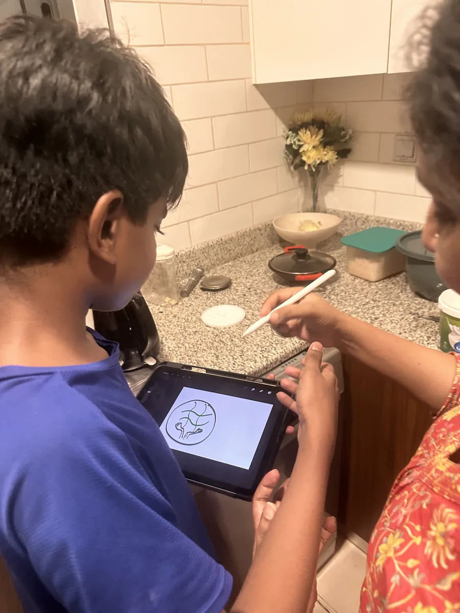 Two children drawing their company logo on a tablet for the GEMS Family Innovation Challenge