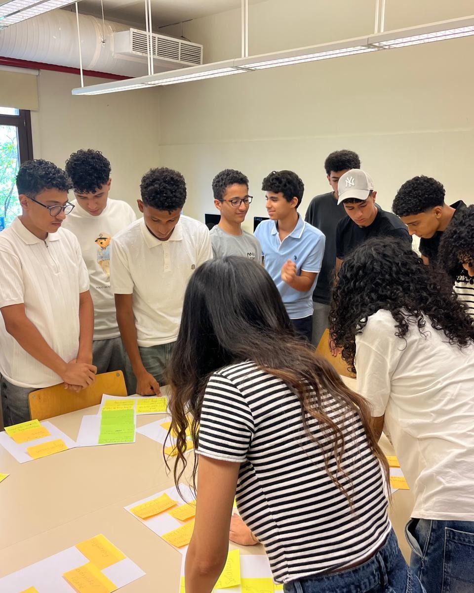 Teenage founders gathered round a table sorting interview evidence