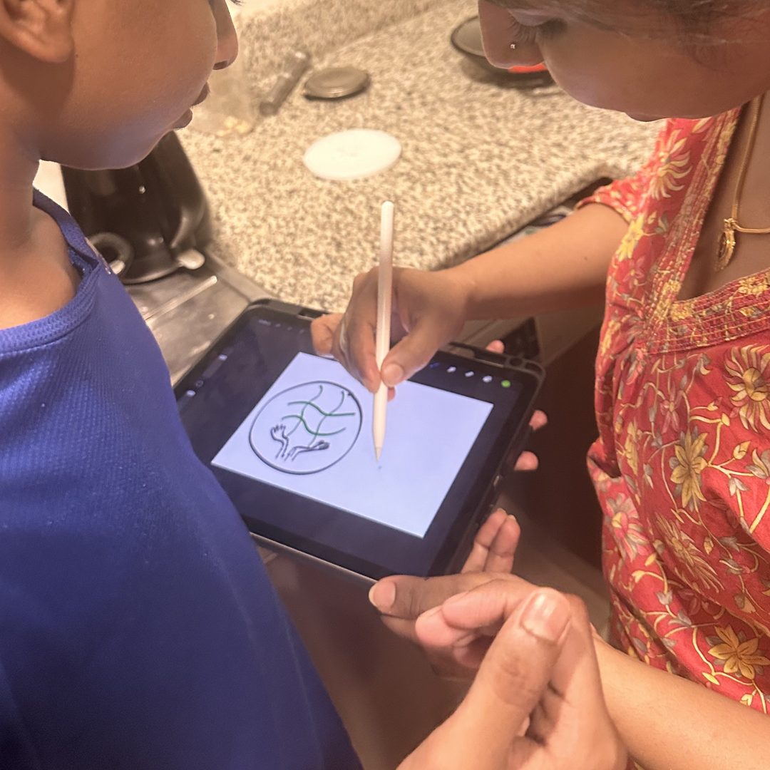 A child and parent drawing a logo on a tablet