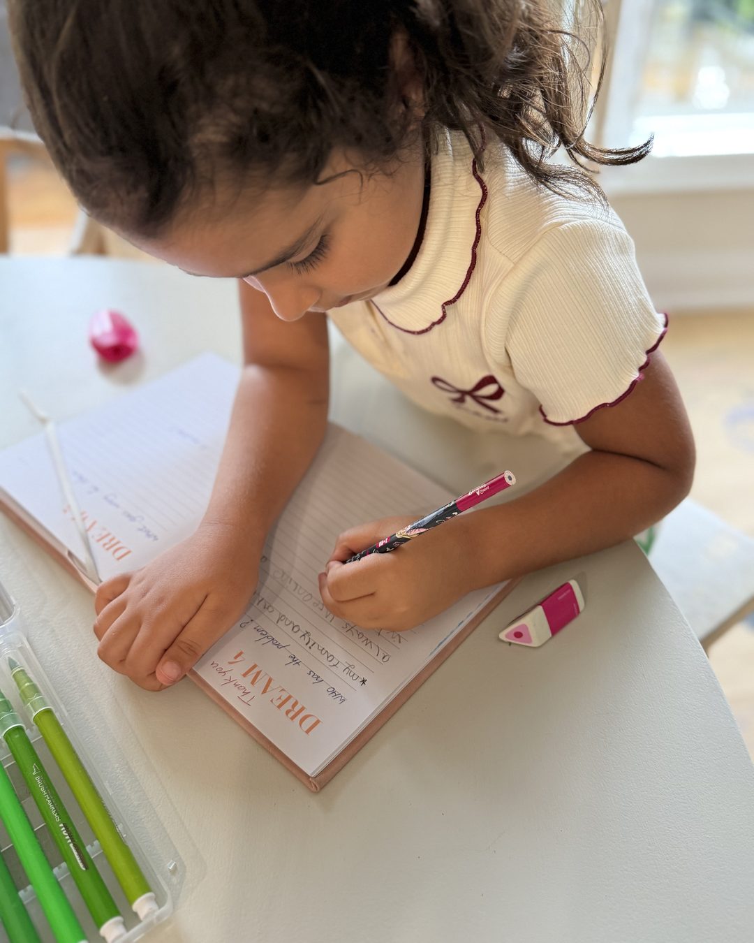A young child writing her idea in a founder notebook